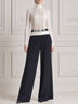 White high-neck fringed top paired with black wide-leg trousers